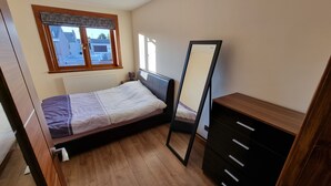 A bedroom with a bed, a dresser, a mirror, and a window. - Captivating 1-bed Apartment in Edinburgh (Edinburgh)