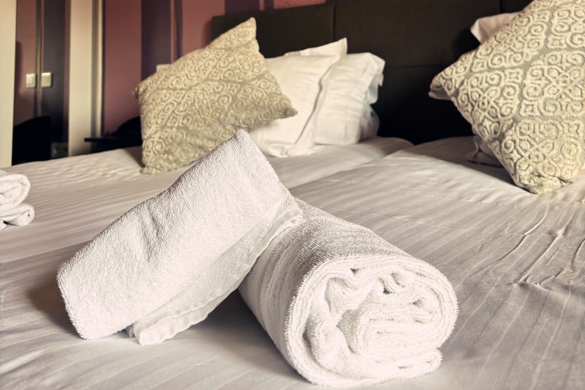 A hotel room with a bed, pillows, and a striped wall.