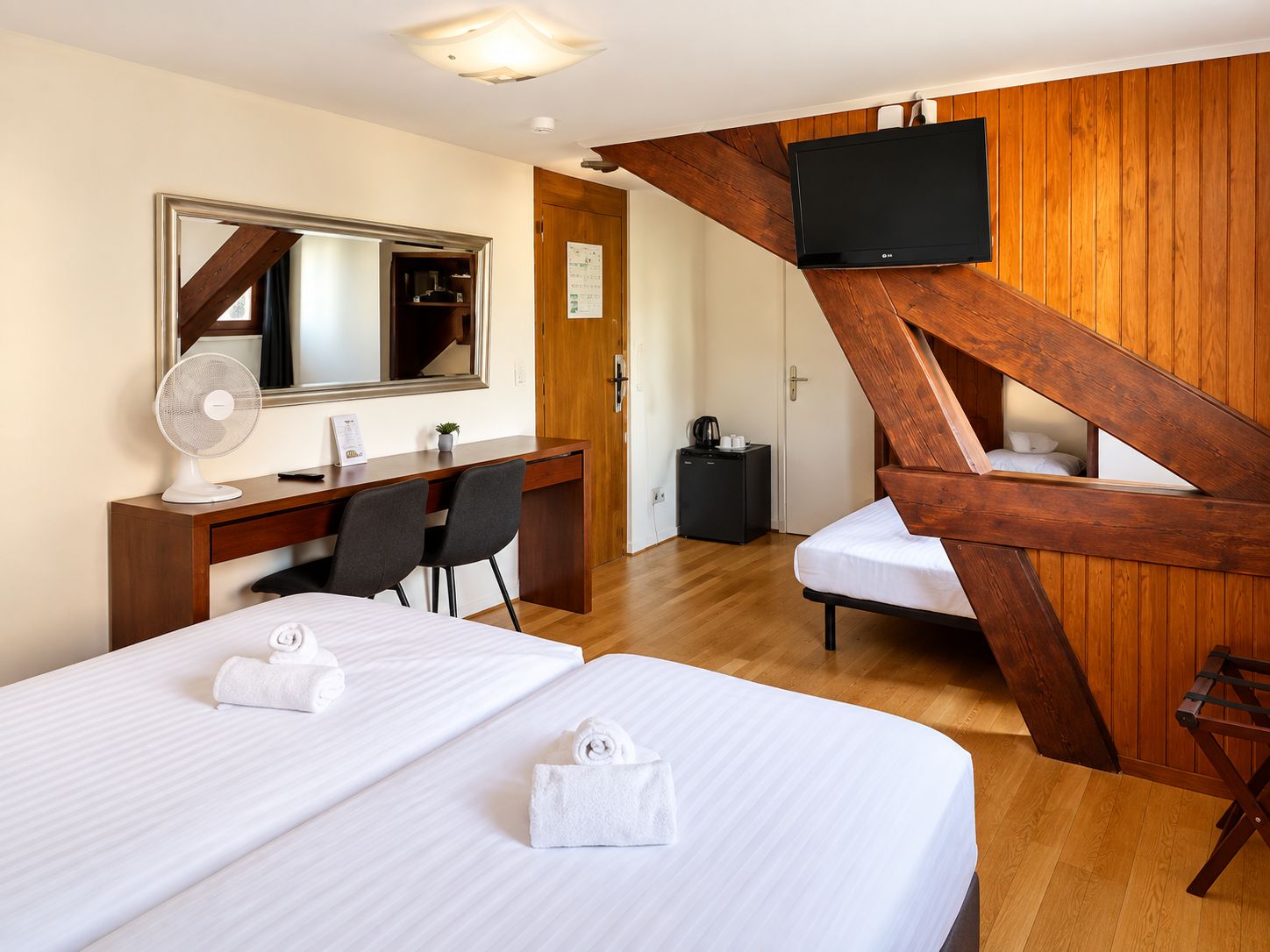 Une chambre d’hôtel avec un lit, un bureau et une chaise, une télévision et un escalier en bois.