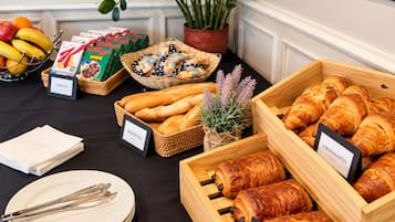 A buffet table with labeled food items including bagels, croissants, and pastries.
