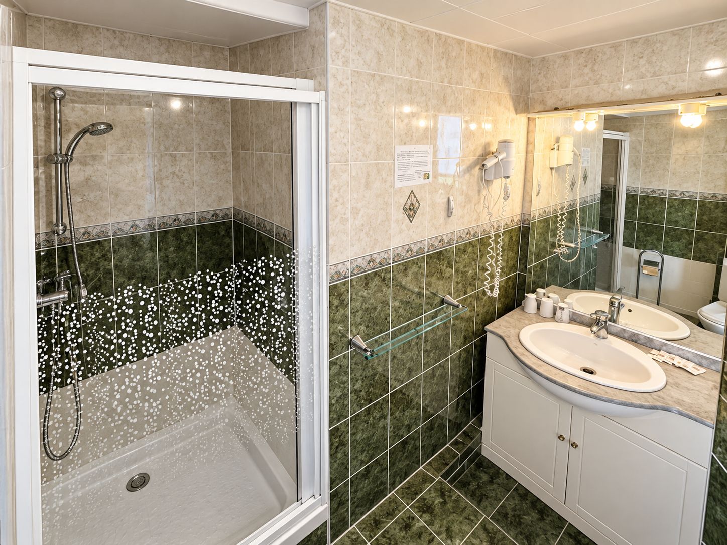 Une salle de bain moderne avec une douche à parois de verre, deux lavabos et un grand miroir.