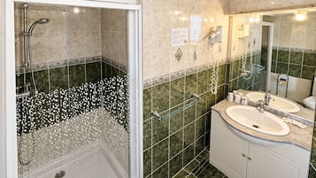 Une salle de bain moderne avec une douche à parois de verre, deux lavabos et un grand miroir.