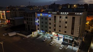 A multi-story building with a prominent 'Sky View Apartments' sign, a ground-level entrance, and a parking area. - Qimam Park Hotel 2 Abha (Abha)