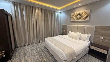 Habitación de hotel con una cama grande, cabecero, una obra de arte colgada en la pared y una cortina.