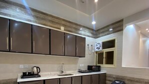 A modern kitchen with dark cabinets, a white countertop, and a built-in oven. - Qimam Park Hotel 2 Abha (Abha)