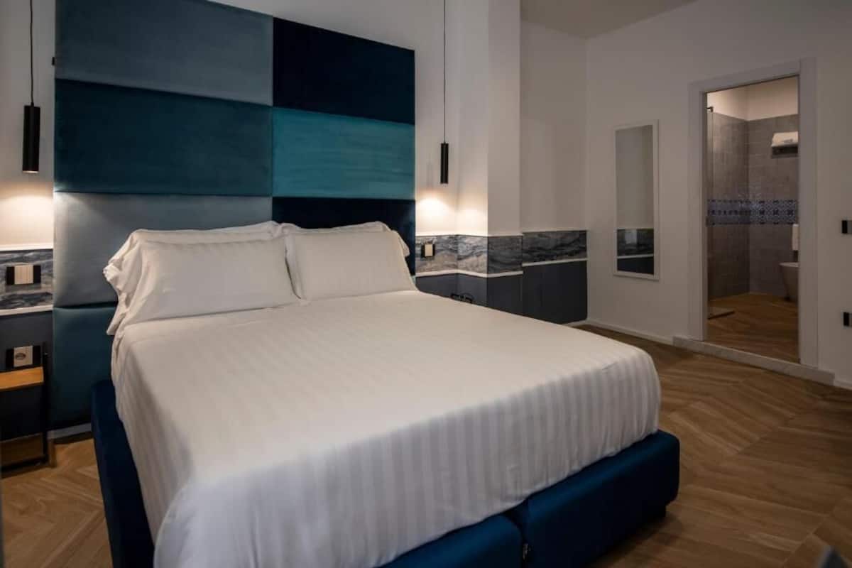 Ein modernes Schlafzimmer mit einem großen Bett, Nachttischen, einem Nachtlicht und einer Wandleuchte.