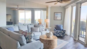 A spacious living room with a large sofa, a round coffee table, and a blue armchair.