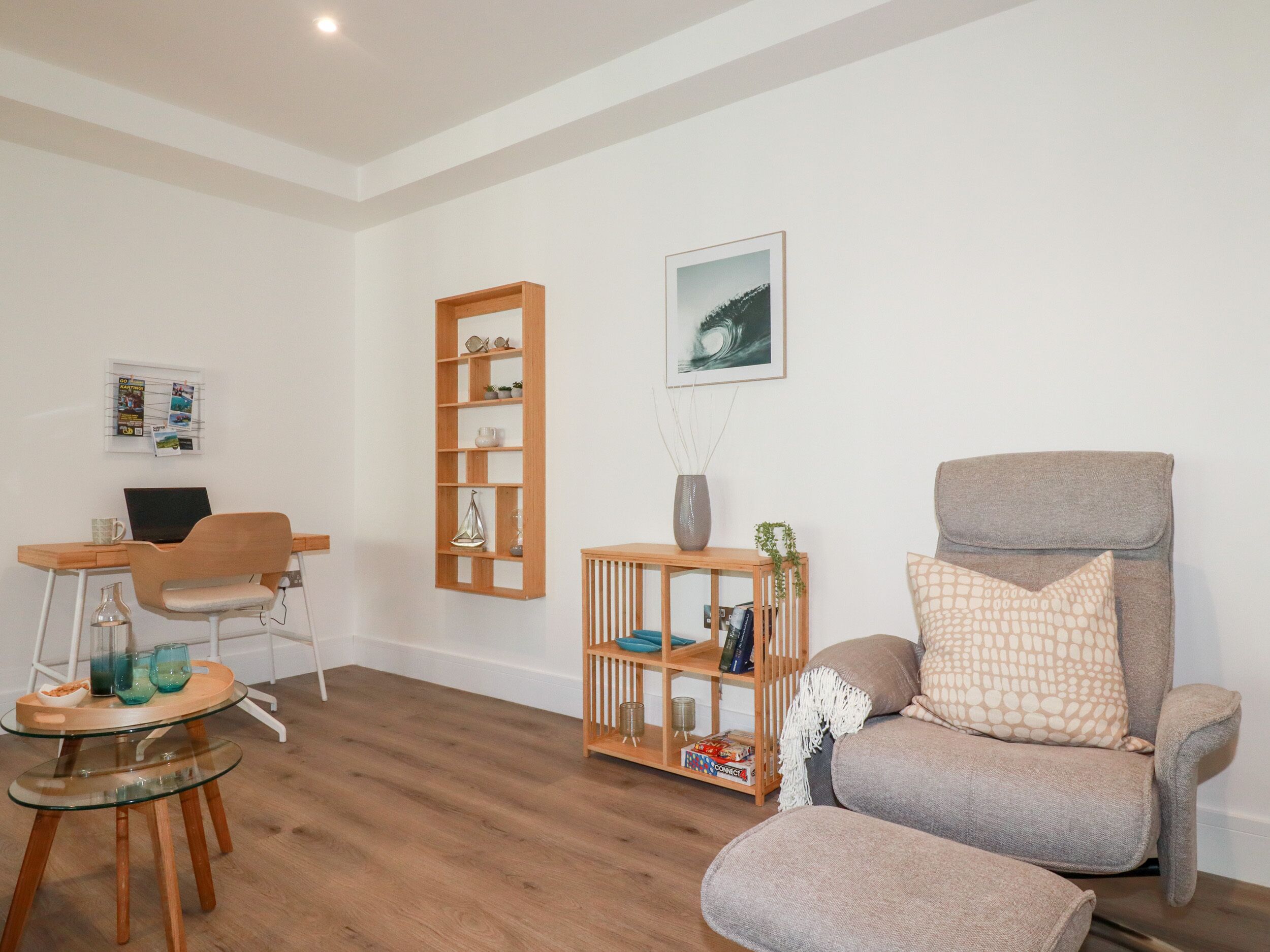 A living room with a wooden desk, a computer, a chair, a sofa, and a bookshelf.