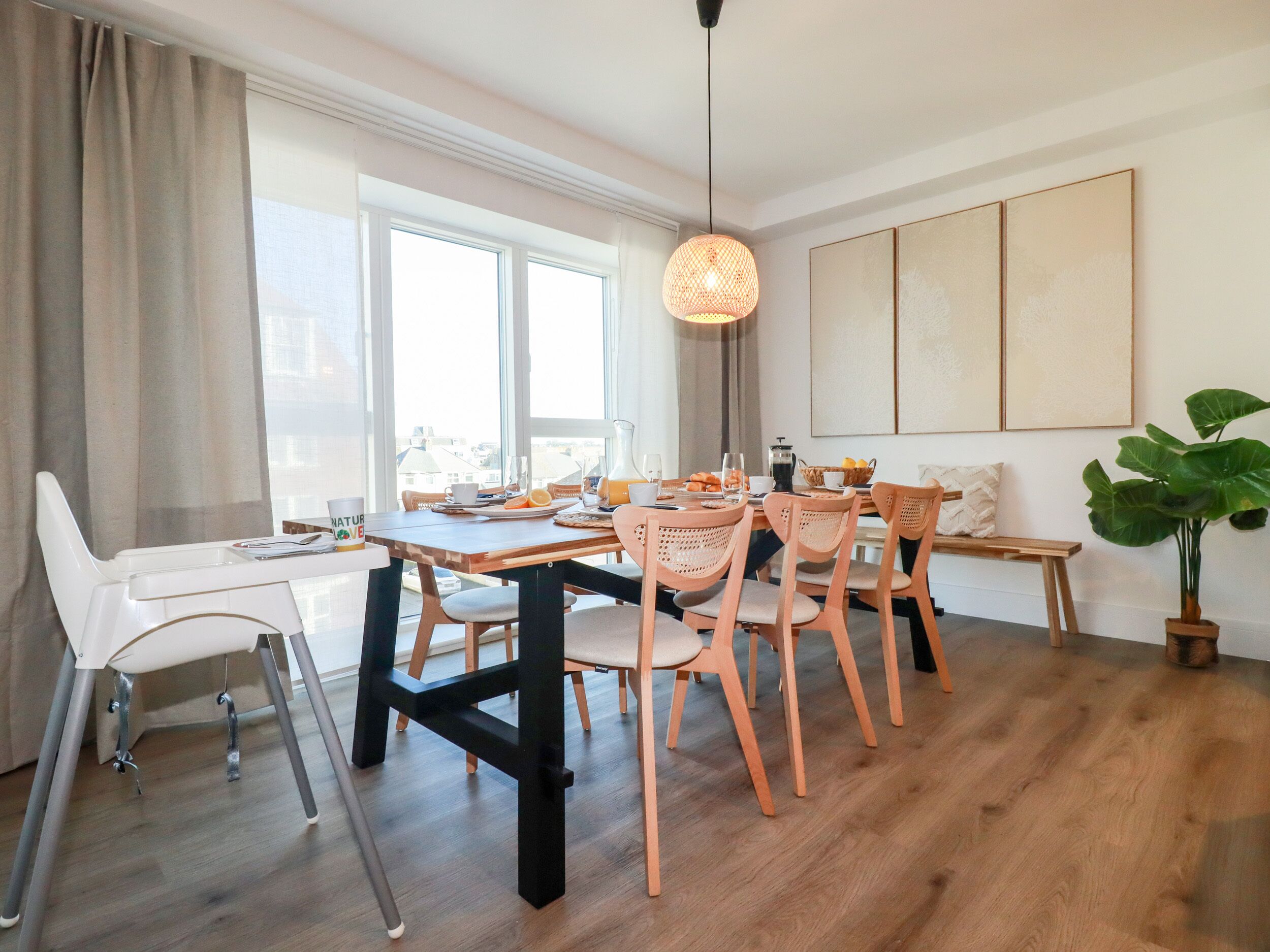 Un espace repas comprenant une table en bois, des chaises et un luminaire suspendu.