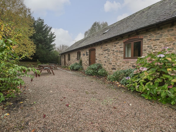 A stone building with a gravel driveway and a picnic table.
