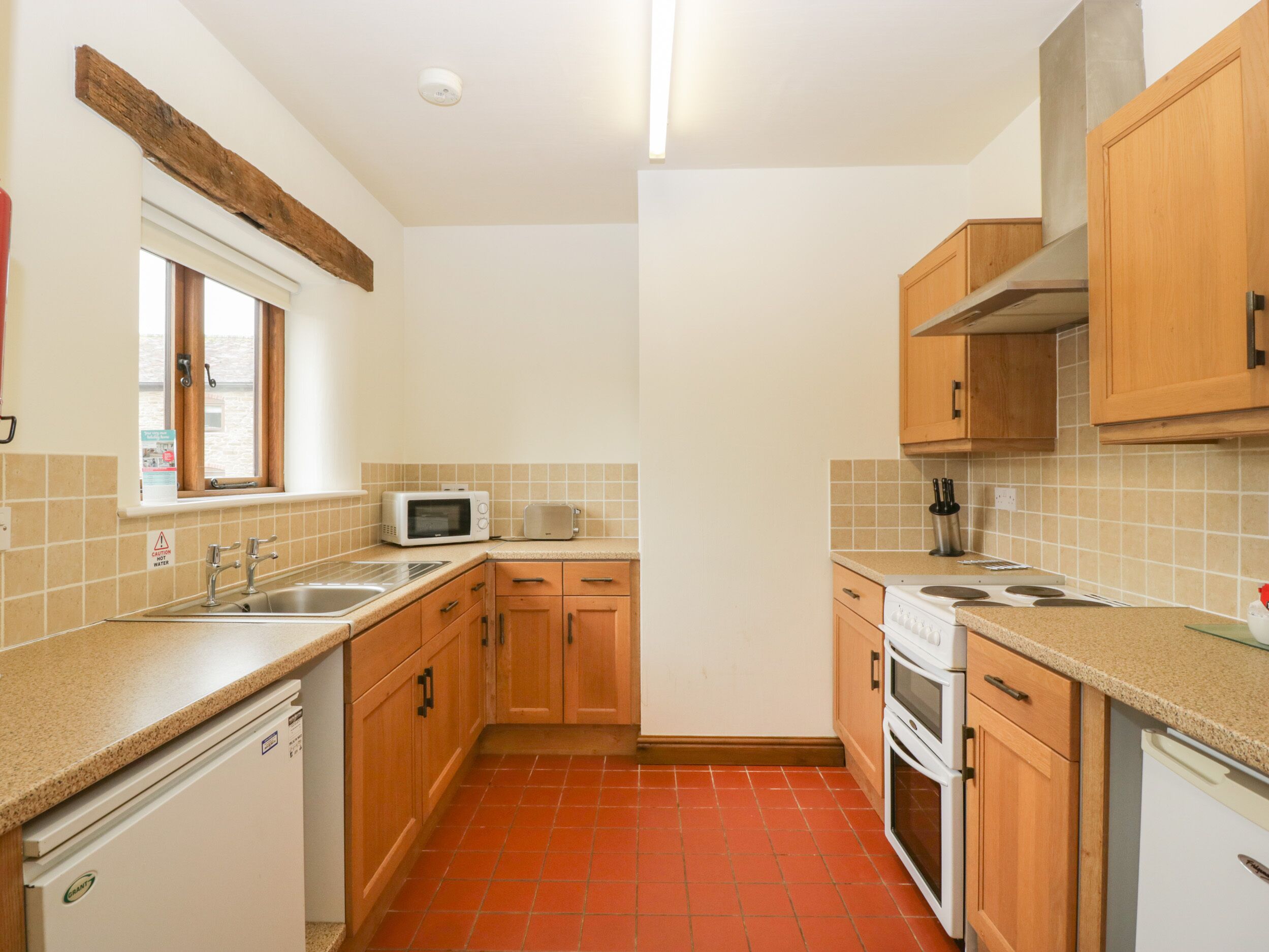 A compact kitchen with wooden cabinets, a microwave, a toaster, and a dishwasher.