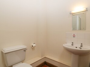 A bathroom with a toilet, a sink, and a caution sign for hot water.
