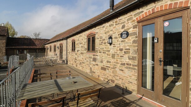 A stone building with a wooden deck, outdoor seating, and a sign reading "CINDER COTTAGE." - Cinder Cottage (Worcester)