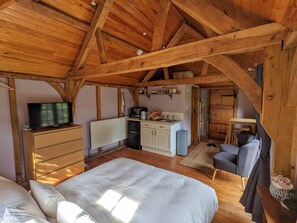 A cozy room with a bed, a small kitchenette, a television, and a wooden ceiling. - Cabin in the Forest. (Brockenhurst)