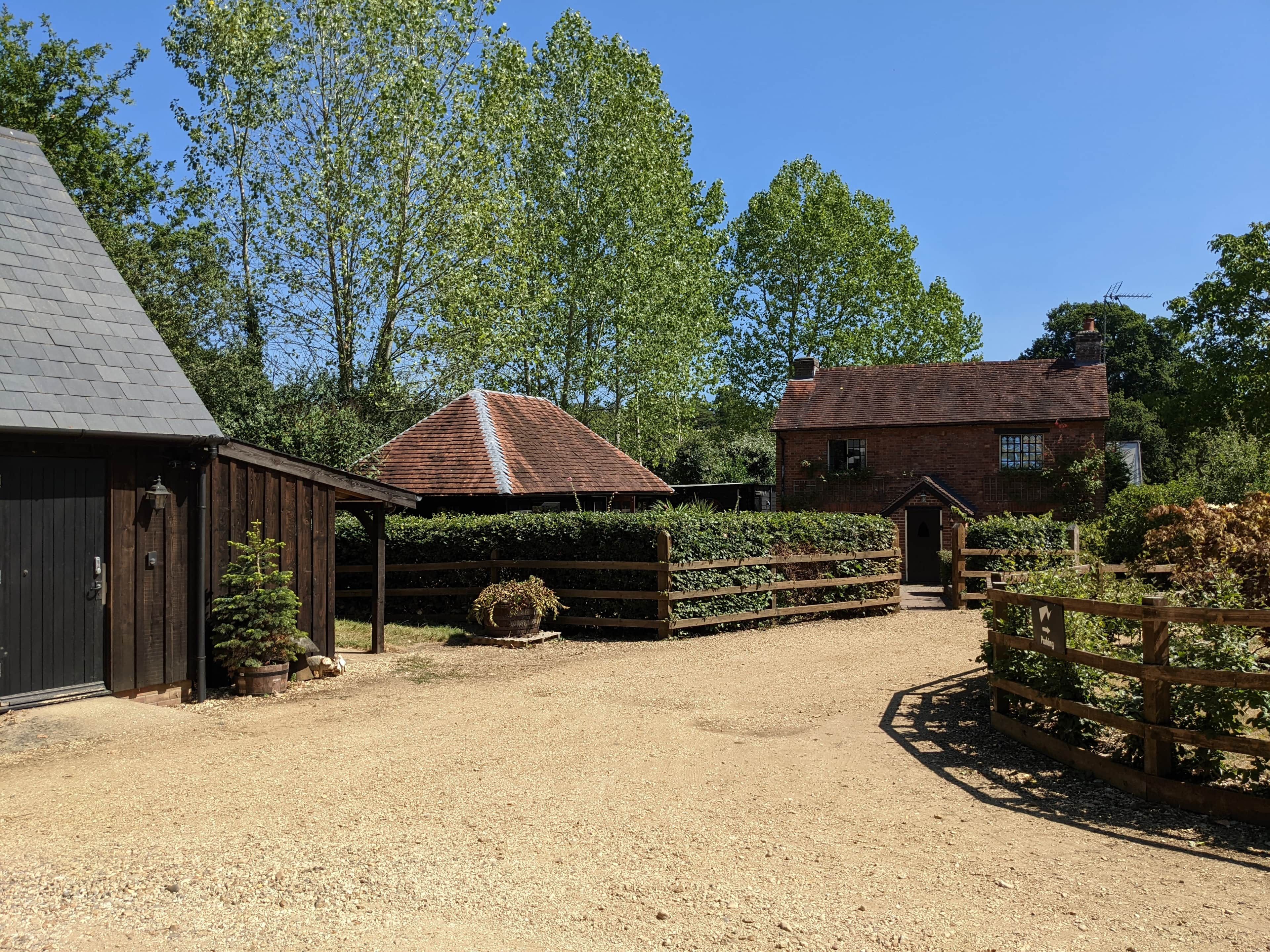A rural property with a stable, a wooden fence, and a gravel driveway.