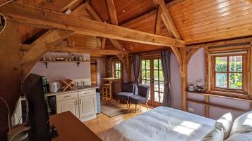 L'intérieur d'une cabane en bois, avec un lit, un bureau et un coin cuisine.