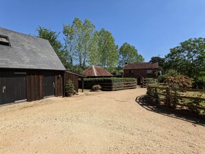 A gravel driveway leading to a barn and a house with a fenced area. - Cabin in the Forest. (Brockenhurst)