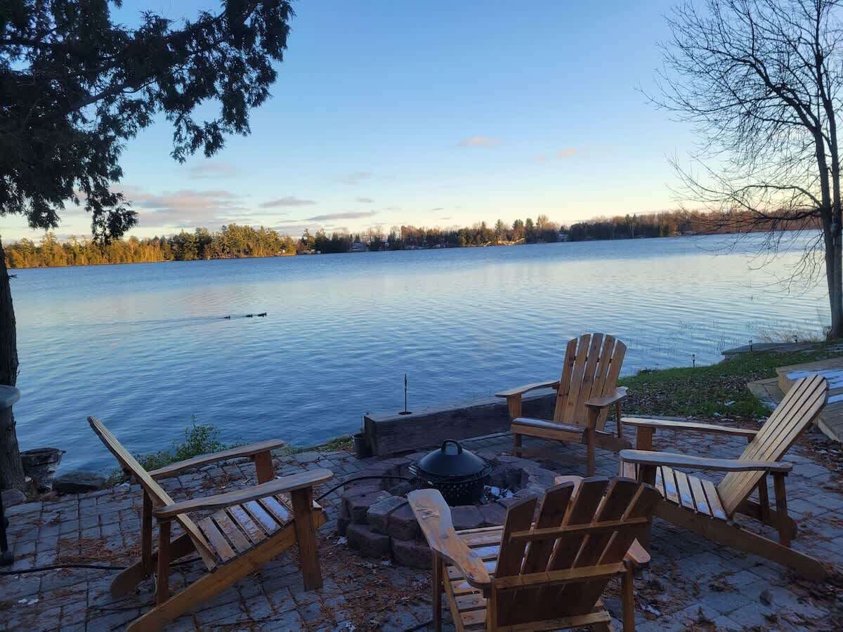 Un espace aménagé au bord du lac, avec des chaises Adirondack et un foyer.