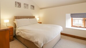 Een slaapkamer met een bed, nachtkastjes, een raam en wanddecoratie.