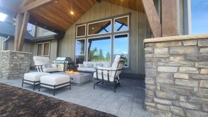 Un patio exterior con paredes de piedra, una chimenea y una zona de estar con dos sofás y sillones.