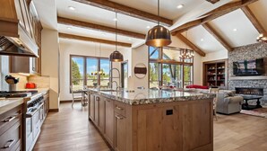 Una cocina amplia con una isla grande, armarios de madera y una chimenea de piedra.