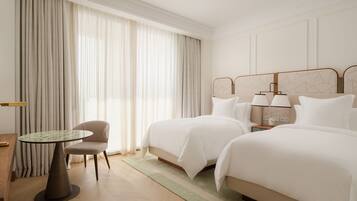 Une chambre d’hôtel avec deux lits, une table ronde, une chaise et une table de chevet avec des lampes.