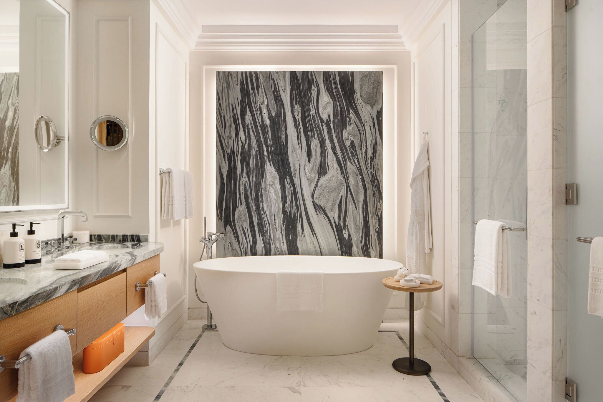 Une salle de bain moderne avec une baignoire sur pieds, une douche à parois de verre et des murs en marbre.