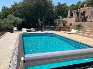 A rectangular swimming pool with clear blue water, surrounded by a tiled deck and white lounge chairs. - Private, cozy room with pool access (Seillons-Source-d'Argens)