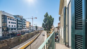 A balcony with a view of a city street, buildings, and a construction crane. - Casa Luar - By Wehost (Funchal)