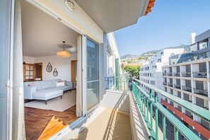 Un balcon avec vue sur la ville, un canapé blanc et un plancher en bois.