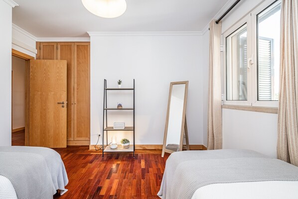 Une chambre à coucher avec des armoires en bois, une table de chevet avec une lampe, un miroir et une fenêtre avec des rideaux.