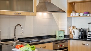 Une cuisine moderne dotée d’une hotte en acier inoxydable, d’un four à micro-ondes encastré et d’une machine à café posée sur le plan de travail.