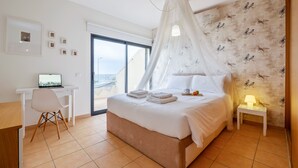 Une chambre à coucher comprenant un lit, un bureau, une chaise, une table de chevet avec une lampe et une fenêtre donnant sur un paysage agréable.