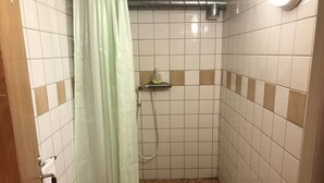 A small, tiled shower area with a showerhead, a soap dispenser, and a curtain. - Ramsjö Camping (Ramsjö)