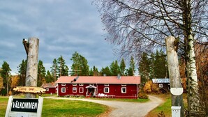 A red building with a white door, surrounded by trees and a sign that reads "Valkommen". - Ramsjö Camping (Ramsjö)
