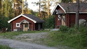 Two wooden cabins with simple designs, surrounded by dense forest. - Ramsjö Camping (Ramsjö)