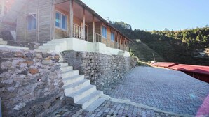 Un bâtiment rustique en bois, doté d’un escalier en pierre menant à un porche.