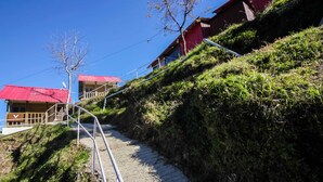 Un escalier menant vers le haut d’une pente herbeuse, avec un bâtiment rouge en arrière-plan.