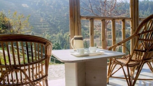 Une pièce avec une table et des chaises, et une fenêtre donnant sur un paysage vallonné.