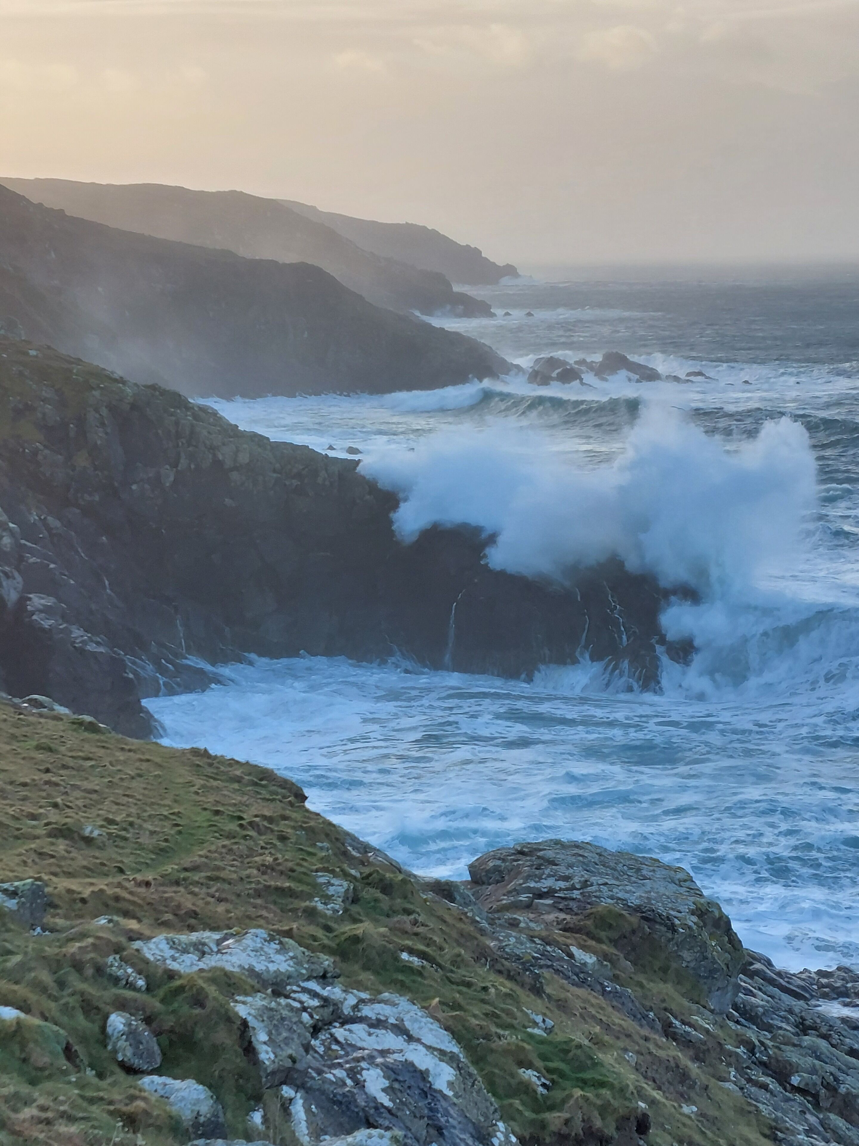 Un paysage côtier caractérisé par des falaises rocheuses et des vagues qui s’y brisent.