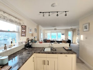A spacious kitchen with a large island, a dining area with a view, and a living room with a sofa and a coffee table.