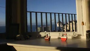Un balcón con barandilla, una mesita y dos barcos modelo.