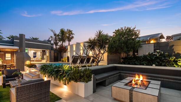 A modern outdoor patio with a pool, fire pit, and comfortable seating areas. - Rancho Relaxo (Cape Town)