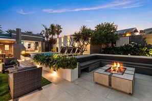 A modern outdoor patio with a pool, fire pit, and comfortable seating areas. - Rancho Relaxo (Cape Town)