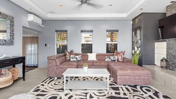 Un salon moderne avec un canapé d’angle, une table basse blanche et un tapis à motifs.