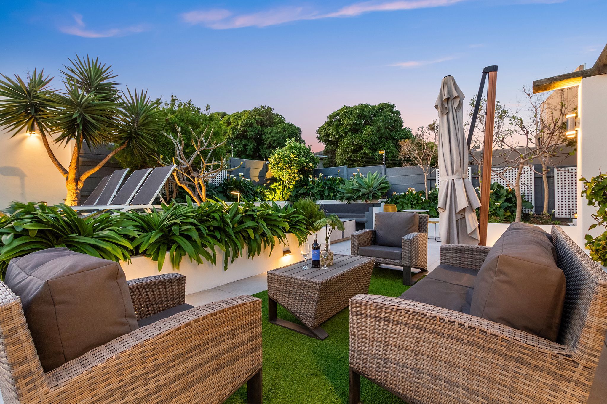 An outdoor patio area with wicker furniture, artificial grass, and solar panels.