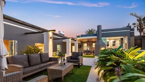 A modern outdoor living area with a sofa, chairs, and a coffee table. - Rancho Relaxo (Cape Town)