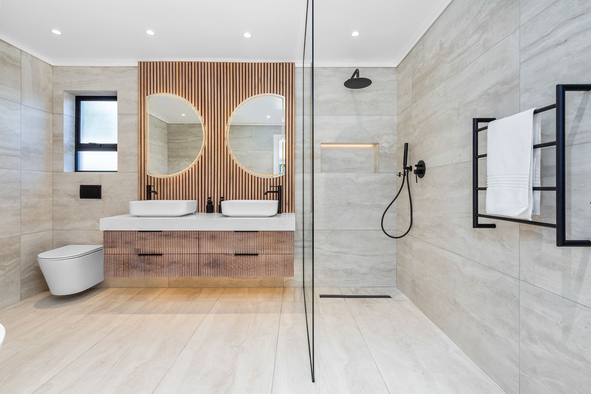 Un bagno moderno con due lavandini, uno specchio grande e un box doccia in vetro.