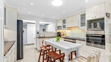 Une cuisine moderne avec des meubles blancs, un îlot central doté de tabourets et un four Bosch.