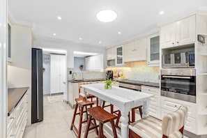 A modern kitchen with white cabinetry, a central island with stools, and a Bosch oven.